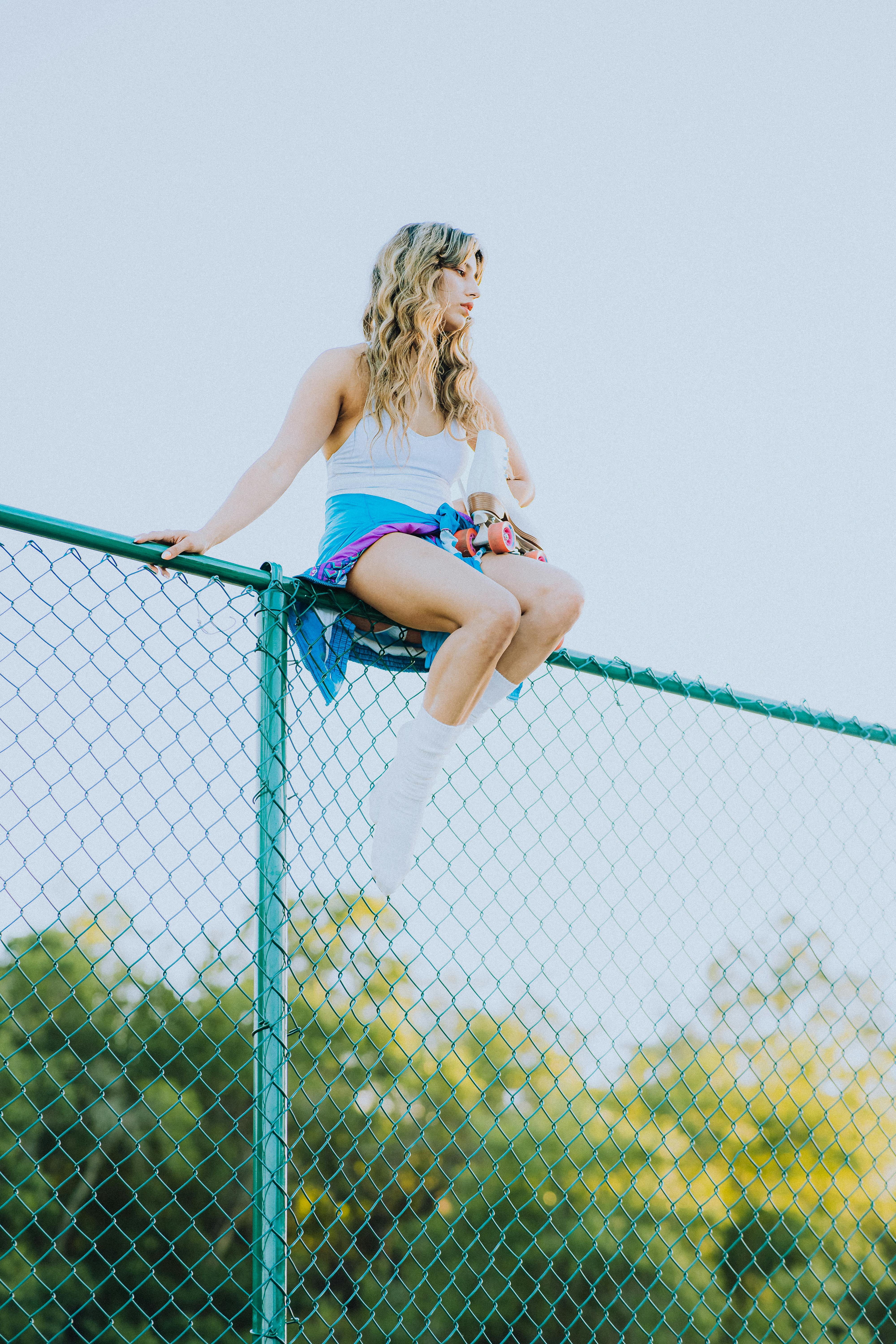 woman sitting on top of a chain link fence