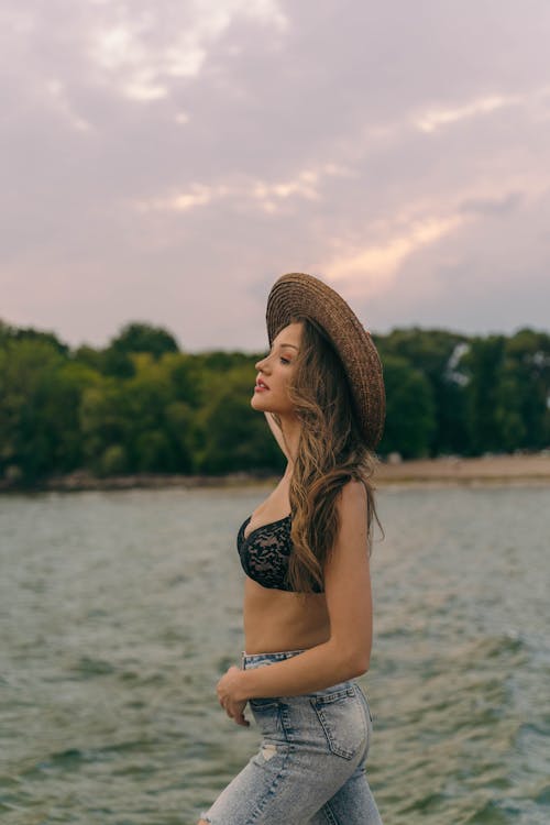 Woman in Hat Standing on a Lake Shore 