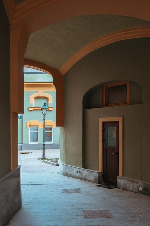 Free Discover a serene urban passageway featuring classic architecture and a vintage lamp post. Stock Photo