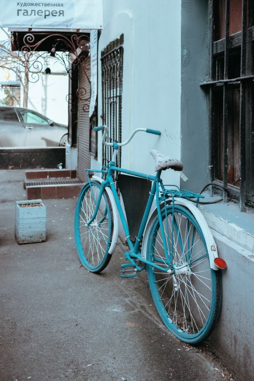 Free A classic teal bicycle parked outside an art gallery, adding charm to the urban street scene. Stock Photo
