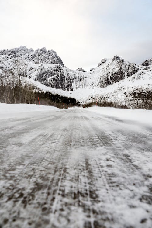 A Snow Covered Road Near a Snow Covered Mountain During Winter