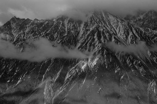 Clouds Covering Snowy and Steep Mountain Range 