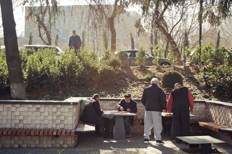 Men Playing Board Games By Tables Outside