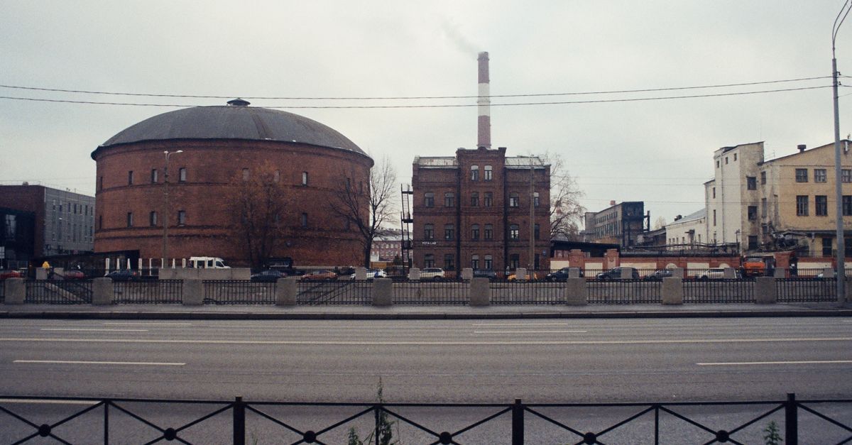 Brick industrial building with smokestack on an overcast day, urban setting.