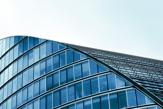 Sleek modern architecture with curved glass facade in an urban setting.