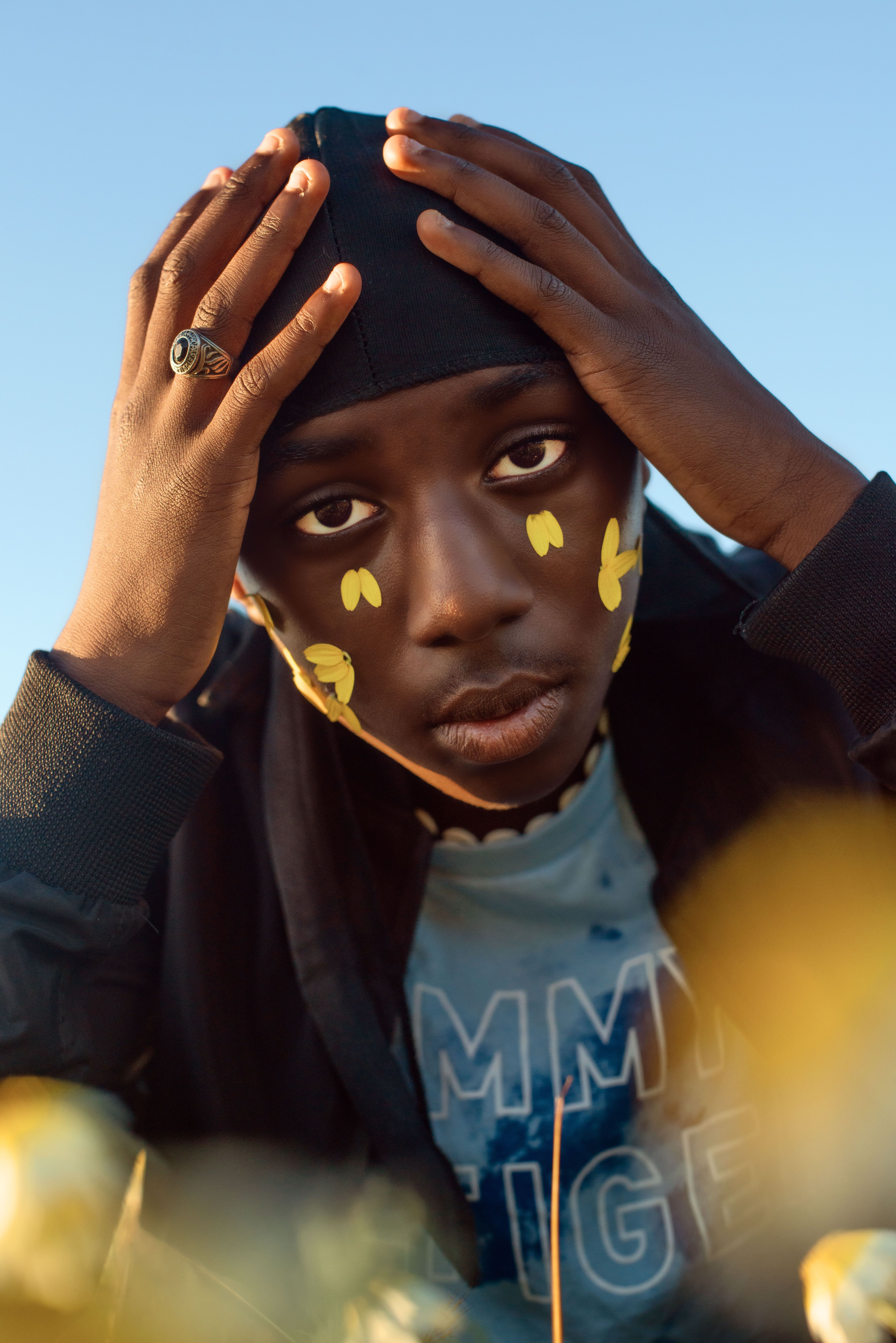 A thoughtful portrait of a young black boy with painted cheeks, exuding creativity and style.