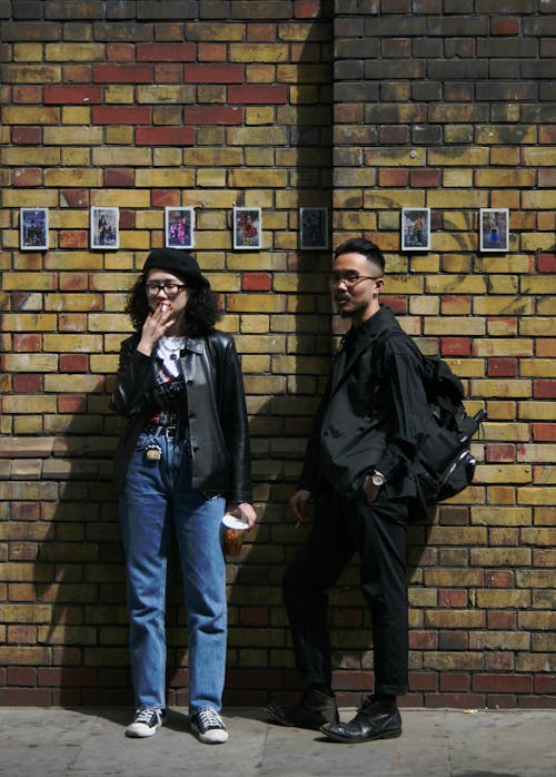 Free Man and Woman Standing in Front of Concrete Wall Stock Photo