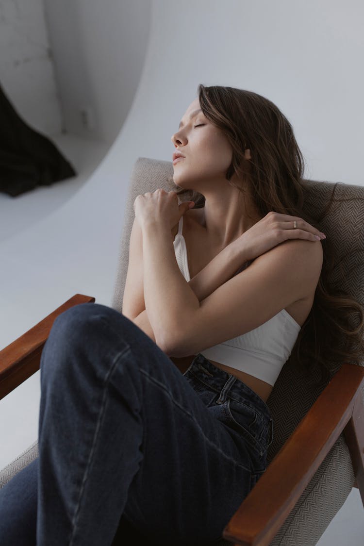 Woman Embracing Herself On An Armchair