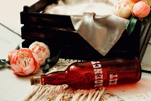 Red Glass Bottle near a Wooden Box