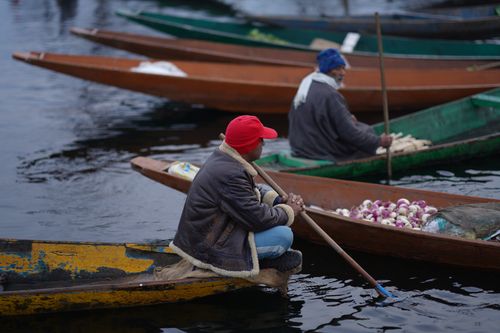 Free Two men in warm clothing sit in wooden boats selling produce on the water. Stock Photo