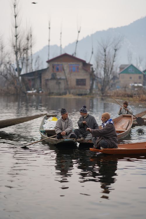 Free Three fishermen conversing on boats on a serene river in autumn. Stock Photo