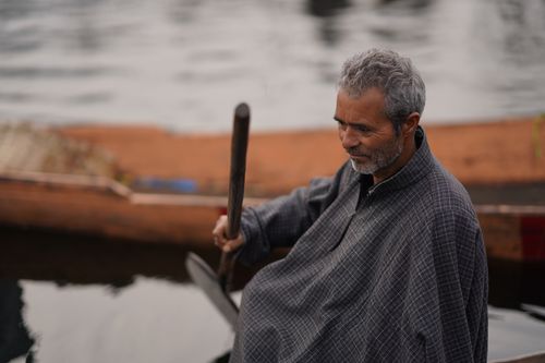 Free A senior man with gray hair rowing a wooden boat on calm waters, showcasing tranquility. Stock Photo