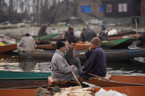 Free A group of men sitting in wooden boats having a conversation on a calm water body. Stock Photo