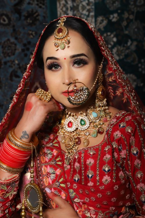 Free Stunning Indian bride wearing intricate jewelry and vibrant red saree for a traditional wedding. Stock Photo