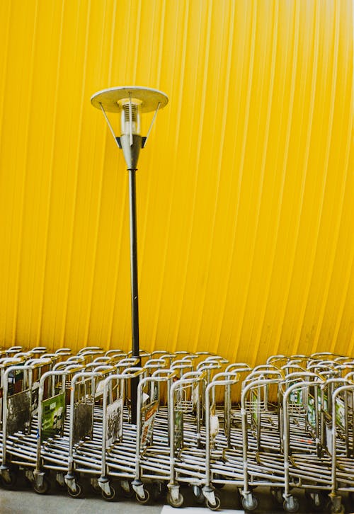 Kostnadsfria Kostnadsfri bild av bagagevagnar, gul vägg, metall Stock foto