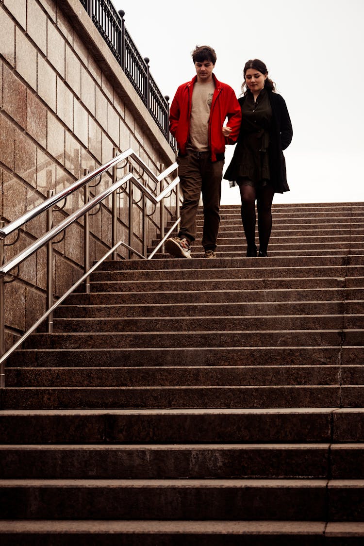 Young Couple Walking Down The Stairs In City 