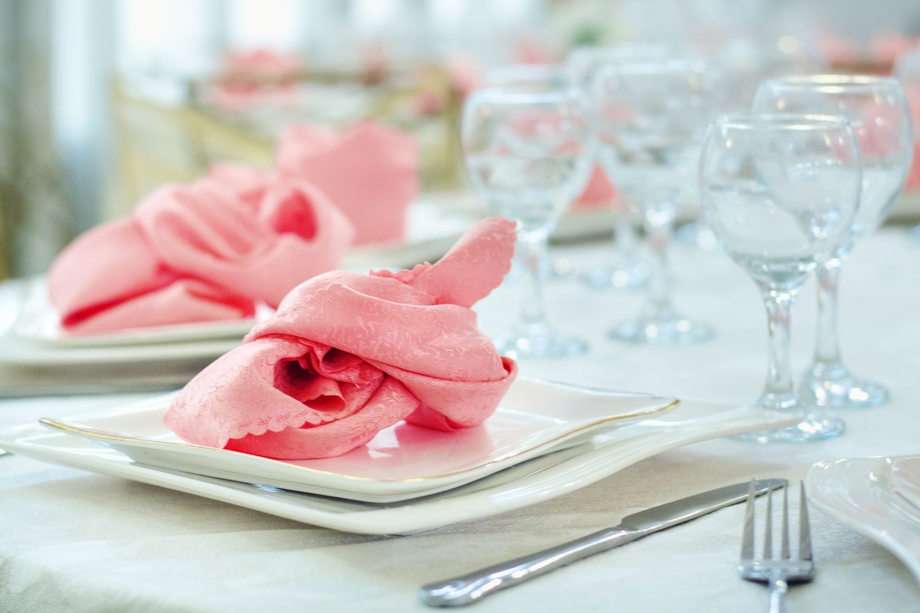 Luxurious dining table setting with pink napkins and wineglasses, perfect for elegant occasions.