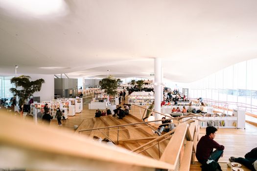 Contemporary library interior filled with people reading and relaxing in a bright and open space.