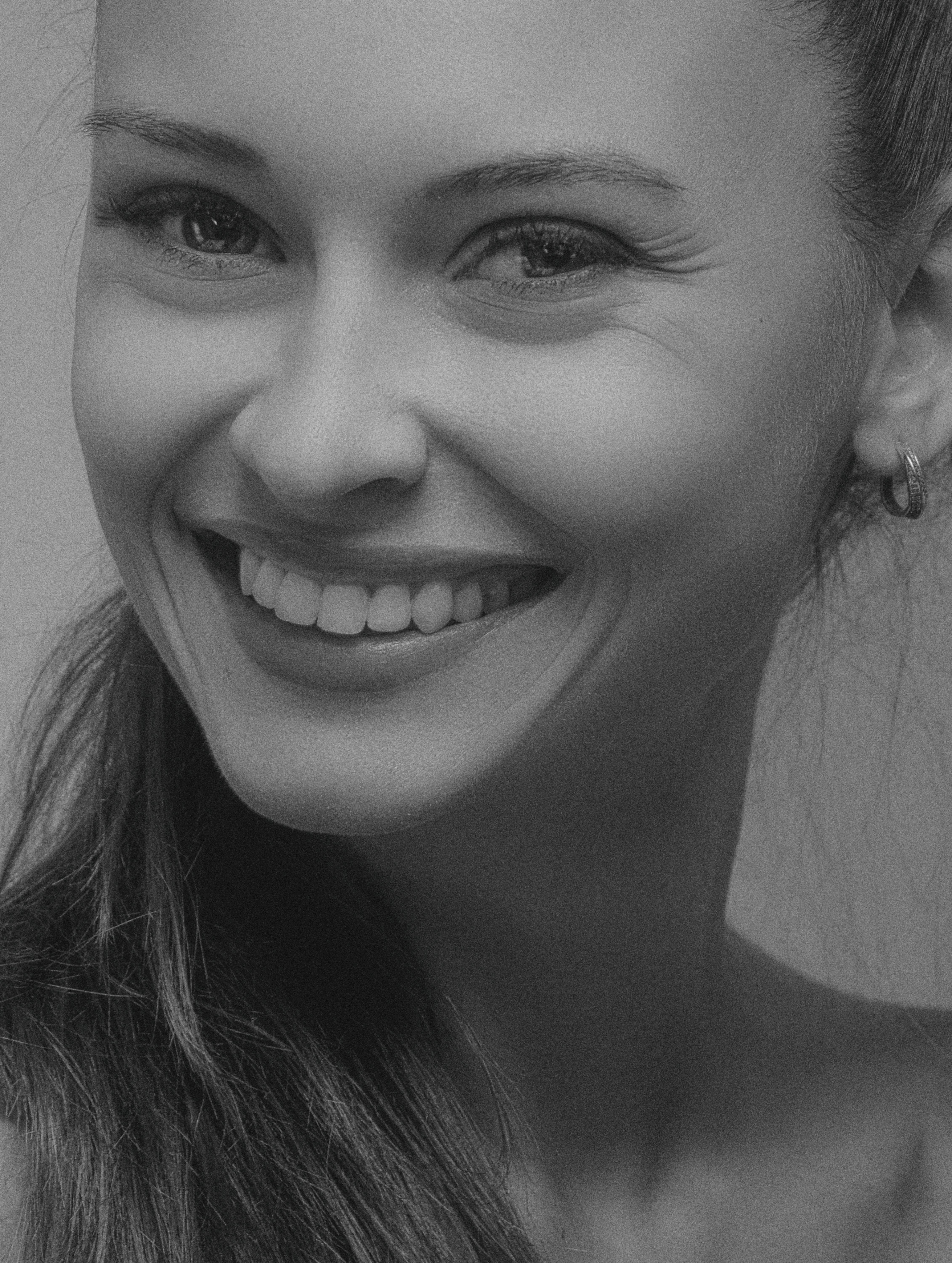 Black and white close-up portrait of a smiling woman with hoop earrings.