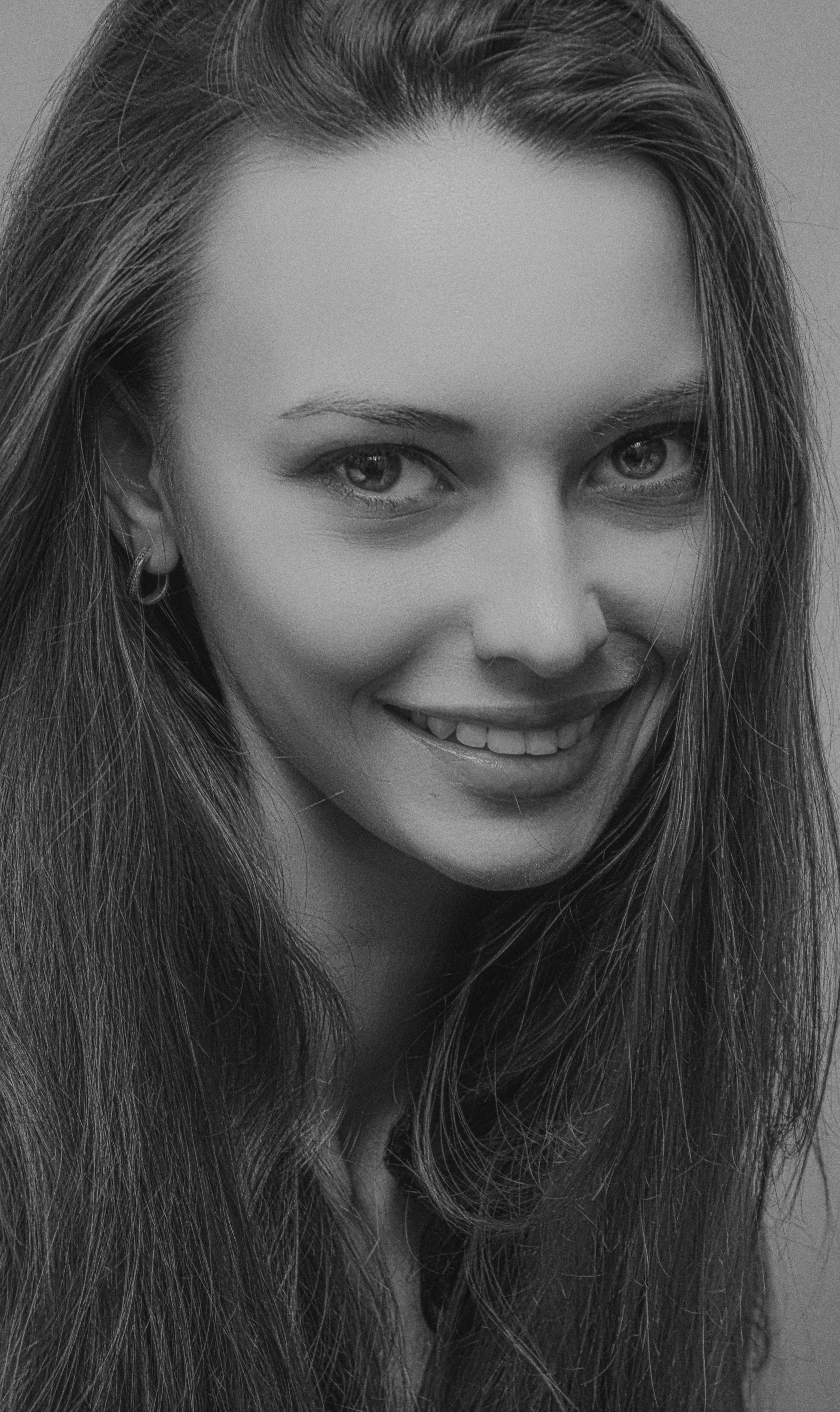 Monochrome portrait of a woman smiling with long hair, showcasing emotions.