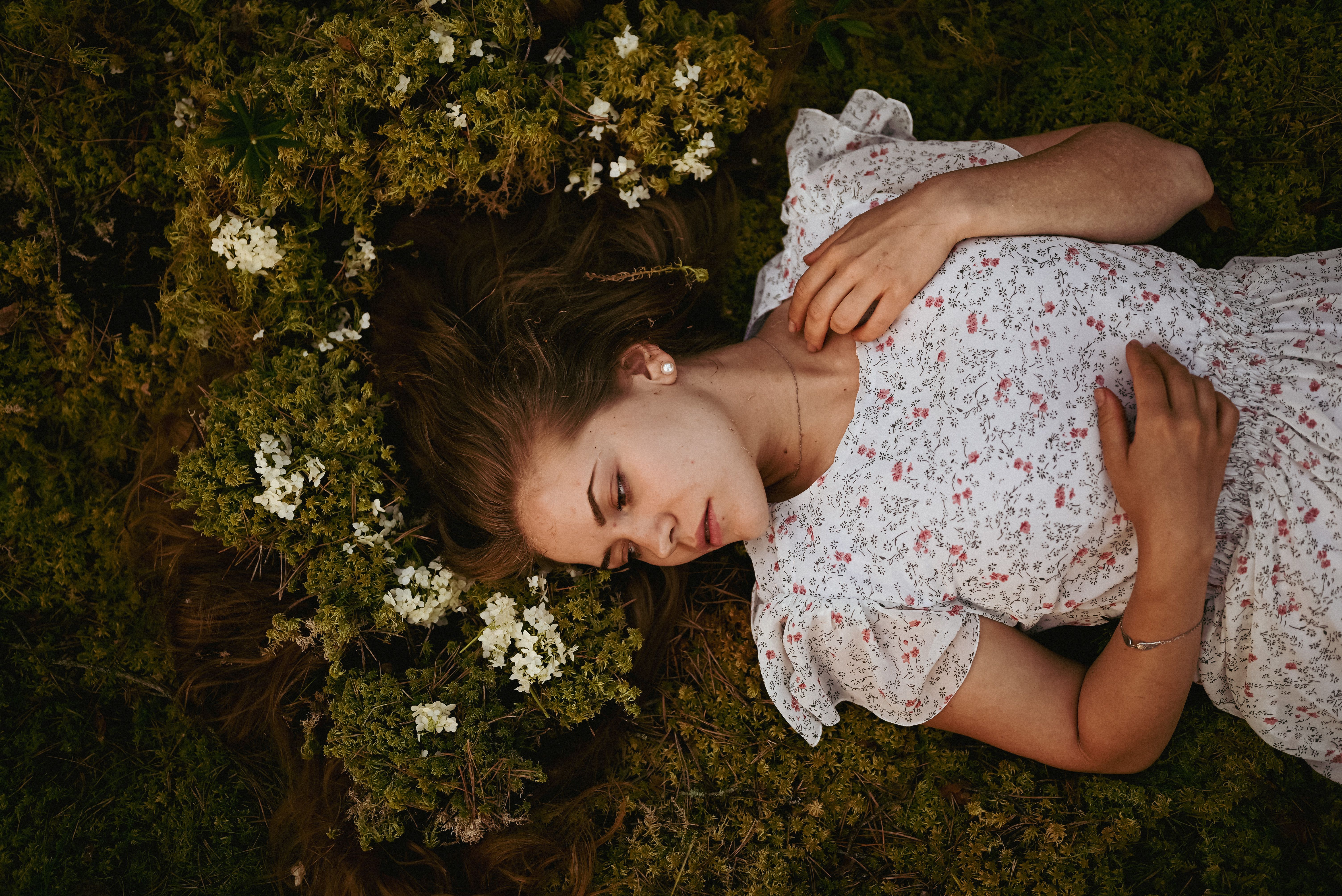 A Woman in White and Red Floral Dress Lying on Green Grass with White ...