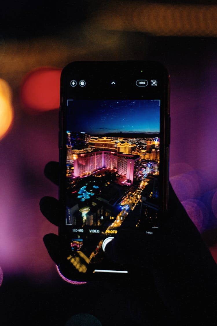 A Person Holding A Cellphone With A Scenic Photo Of Illuminated Buildings