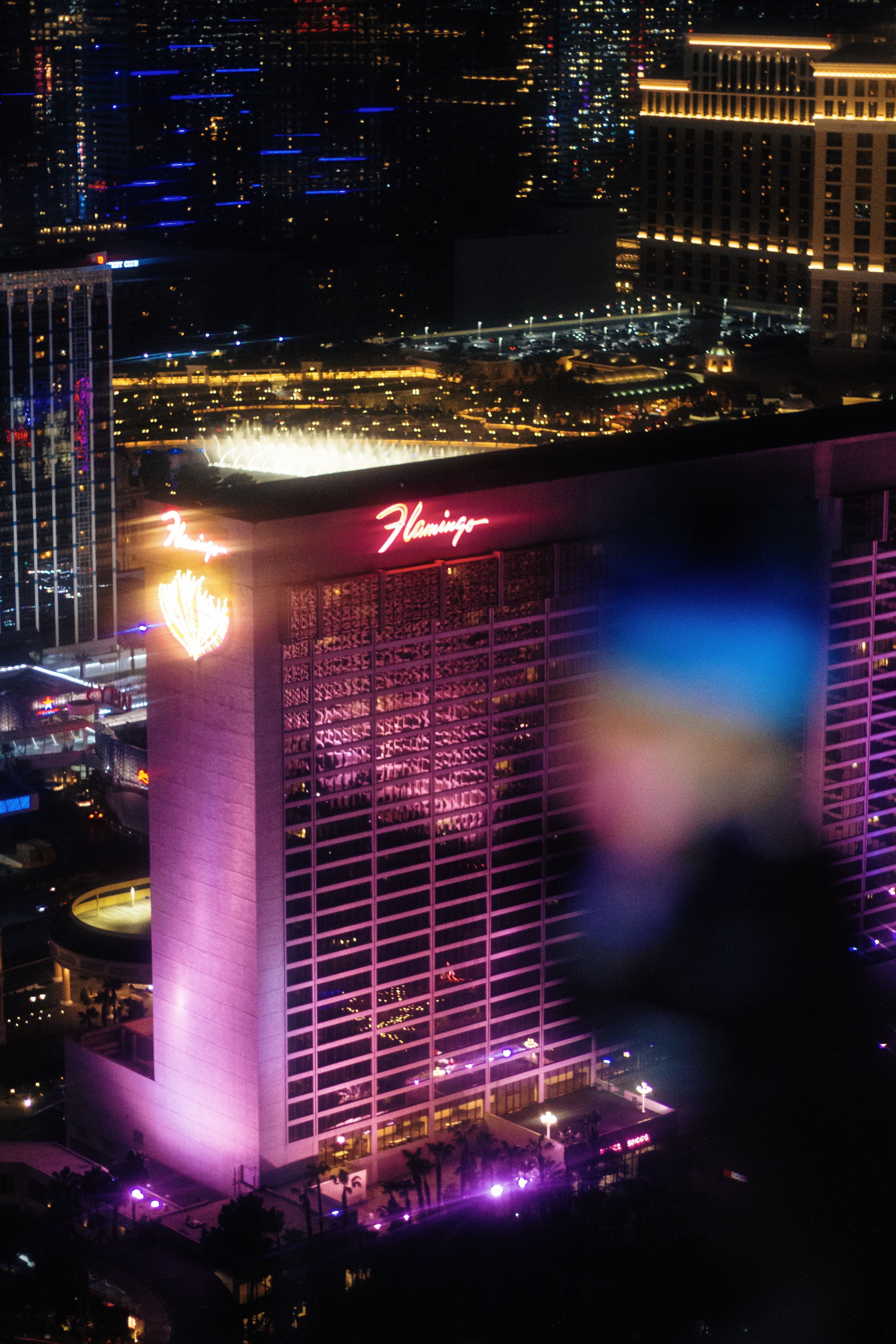 Aerial night view of the iconic Flamingo Hotel in vibrant Las Vegas, glowing with neon lights.