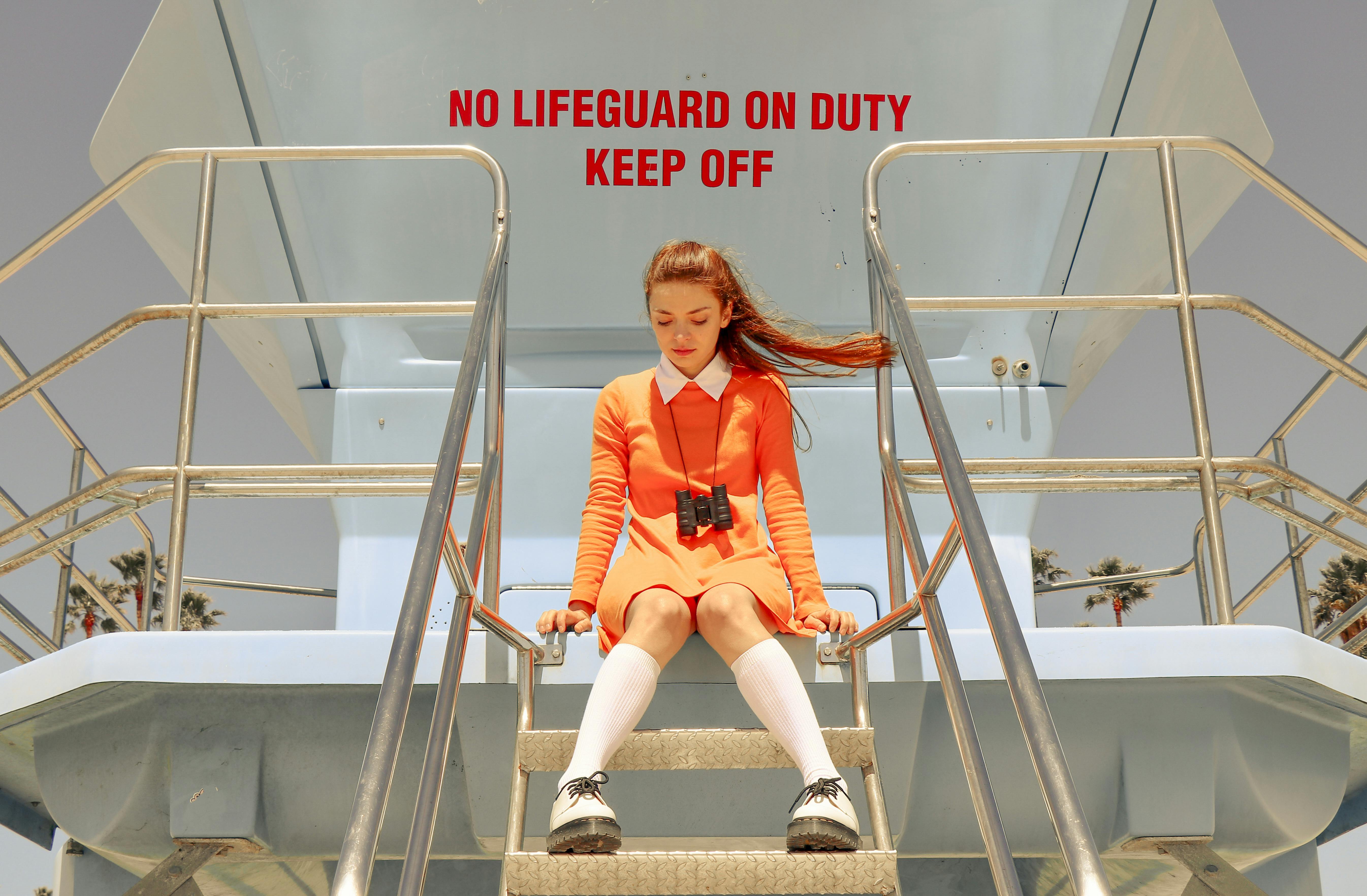 woman in orange dress sitting on top of diving tower