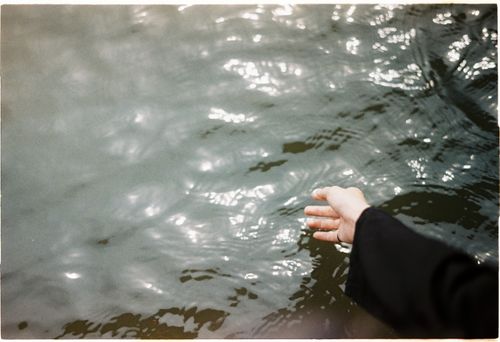Free A hand extends towards a shimmering water surface, capturing tranquility. Stock Photo