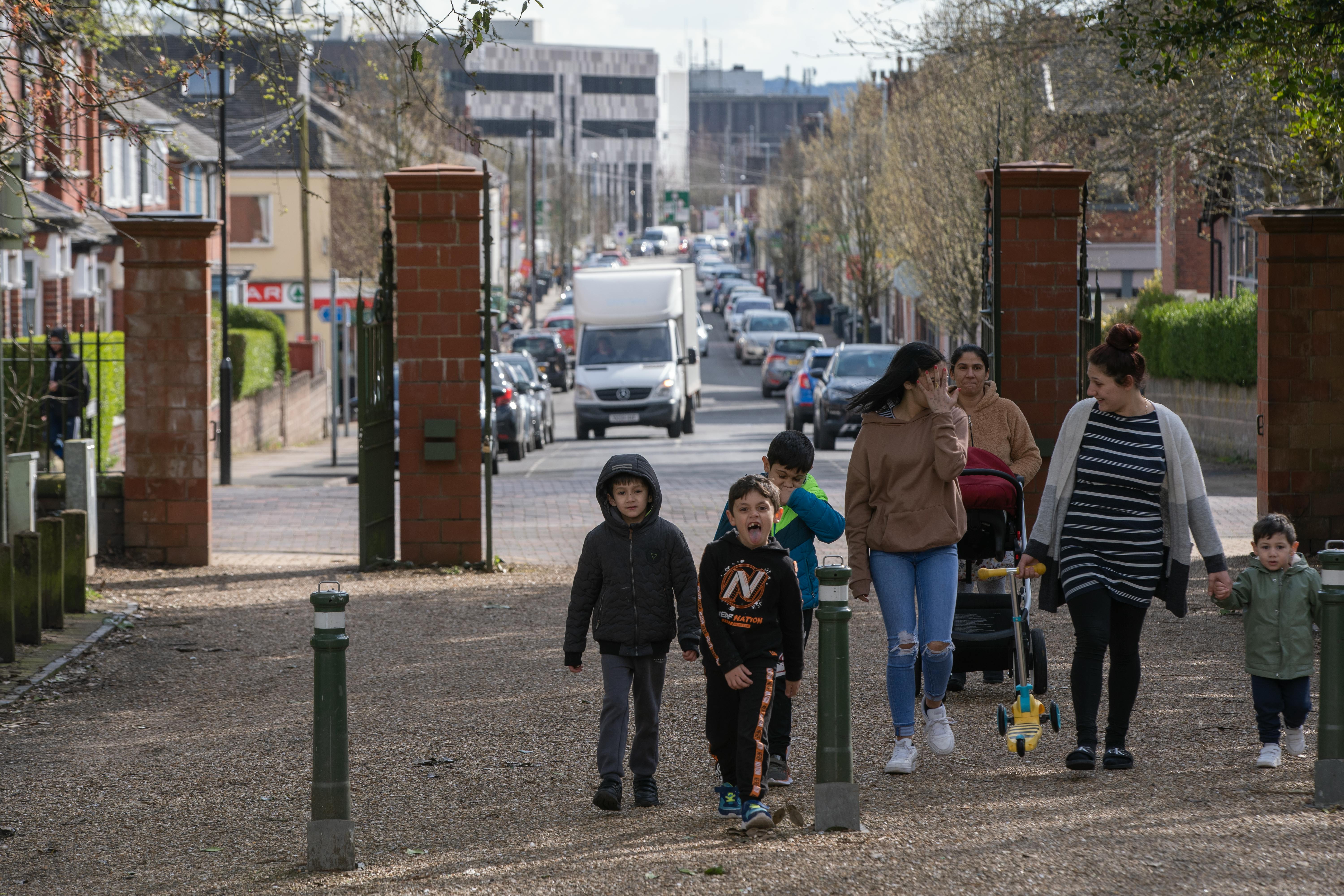 A group of families enjoying a walk on a bustling street in England. Captured during a lively spring day.