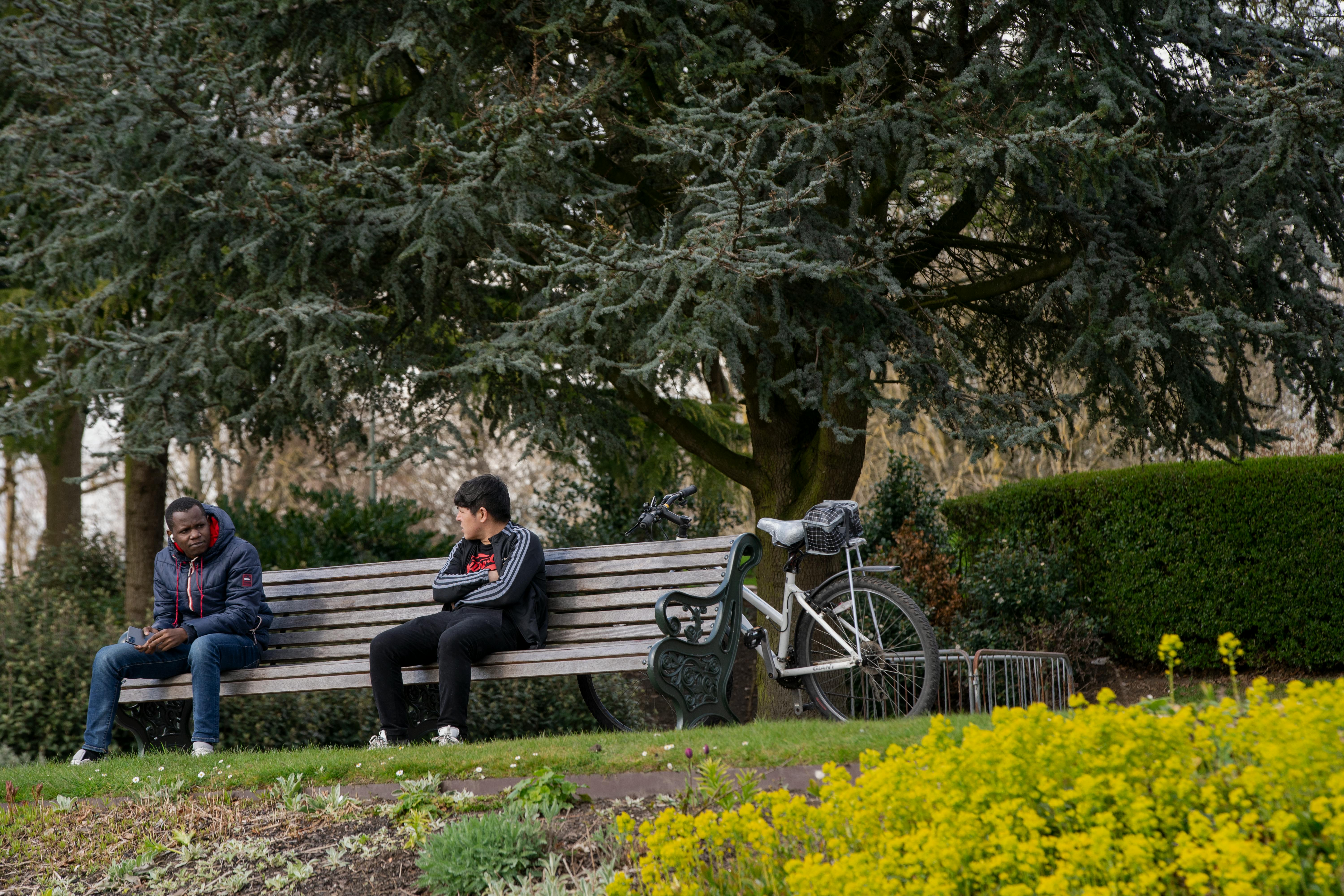 two men sitting on bench in the park