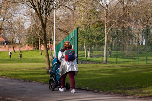 Woman with Child Walking with Stroller in Park
