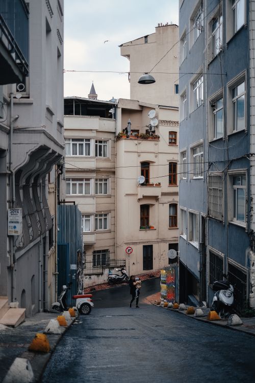 Free A narrow urban street with historical buildings and wet pavement, creating a classic city atmosphere. Stock Photo