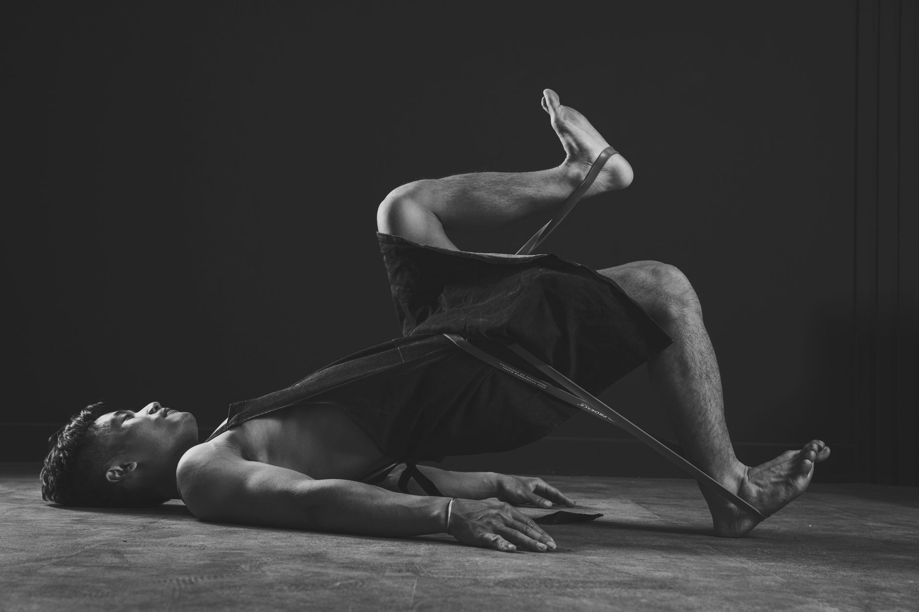 Black and white photo of a man training with resistance bands indoors, focusing on strength and fitness.