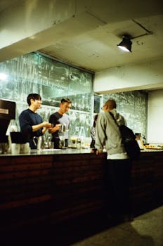Two baristas interacting with a customer at a stylish café counter