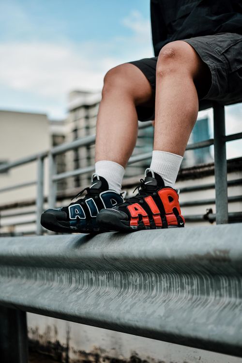 Free Trendy urban sneakers resting on a railing in a vibrant city setting. Perfect for fashion and lifestyle themes. Stock Photo