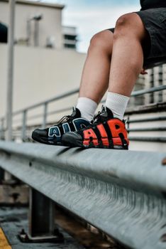 Urban fashion scene with sneakers sitting on a railing in Kuala Lumpur.