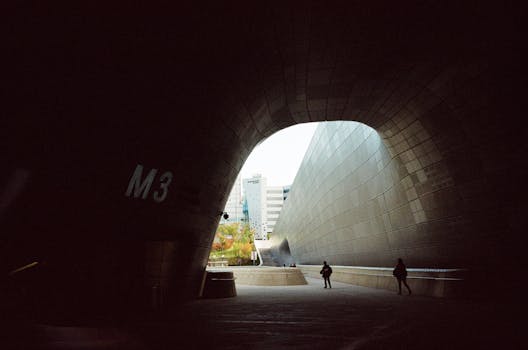 View of Dongdaemun Design Plaza's modern architecture with people in silhouette.