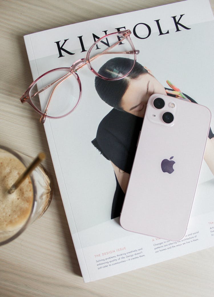 An Iphone And Eyeglasses On Top Of A Magazine