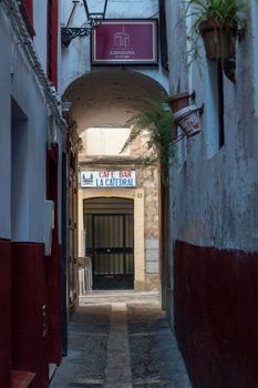 Explore a quaint narrow alley leading to a café bar in a historic European town, perfect for urban exploration.