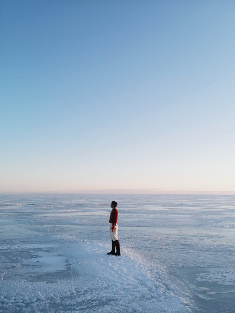 Woman Standing On Frozen Lake At Dawn