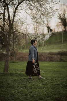 Serene scene of a woman walking through blooming trees in a spring landscape.