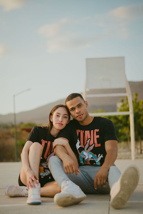 Free Couple Sitting on a Basketball Court  Stock Photo