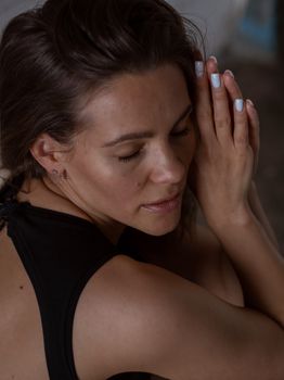 A serene woman with closed eyes and hands together, embodying peace.