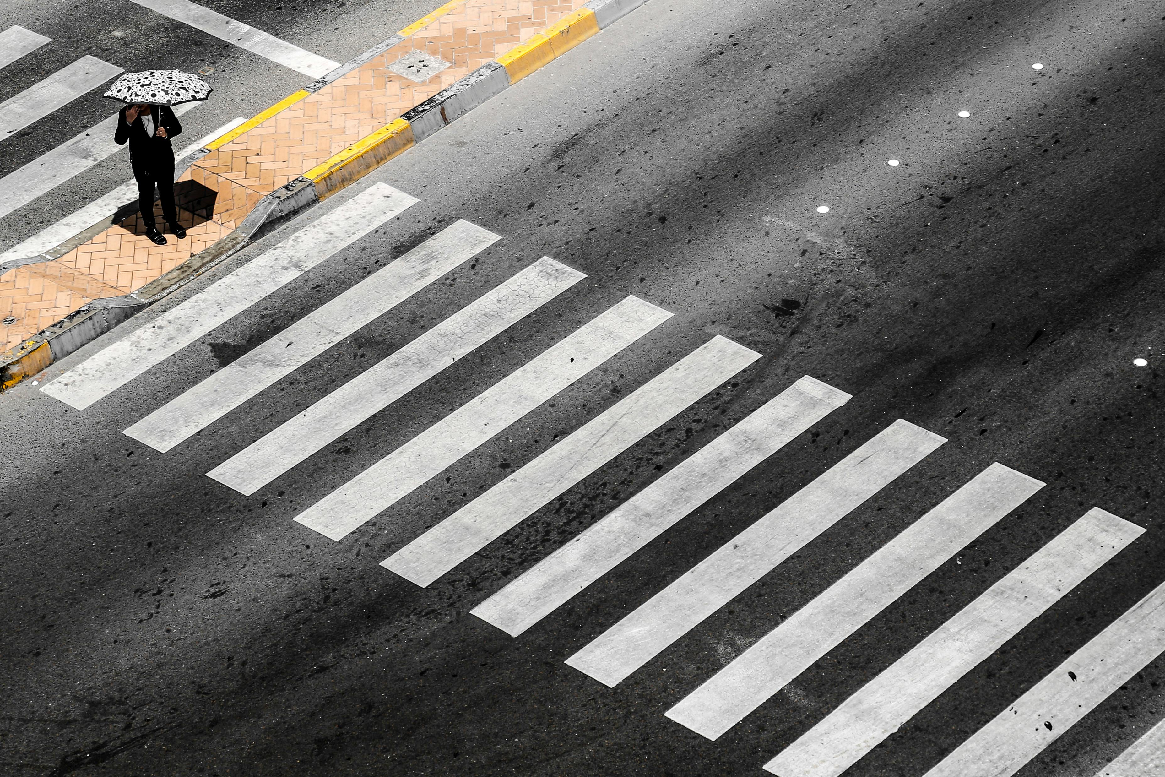 Aerial view of a lone pedestrian with an umbrella at a crosswalk in Abu Dhabi