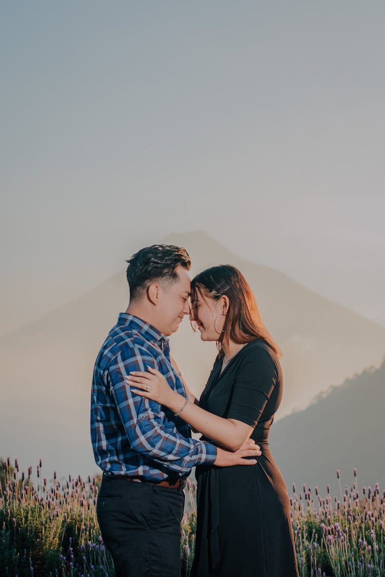 Happy Couple Embracing Against Mountain In Background