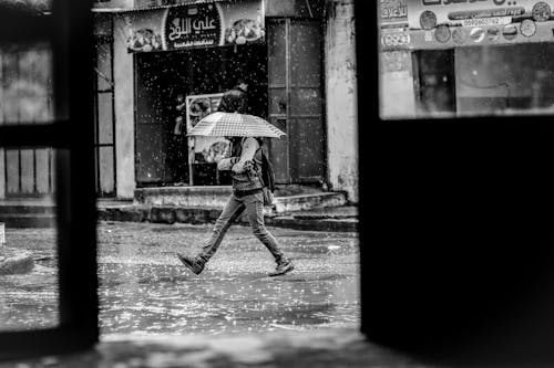 Grayscale Photo of Man Holding Umbrella during Rainy Weather