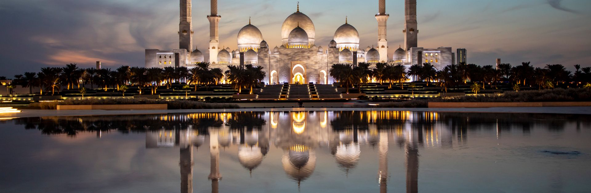Majestic view of Sheikh Zayed Grand Mosque reflecting in the water at dusk, Abu Dhabi, UAE.