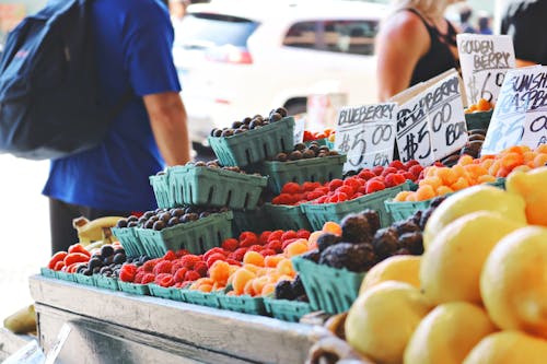 Free Man Wearing Blue Top and Black Bottom Standing Near Fruit Stand Stock Photo