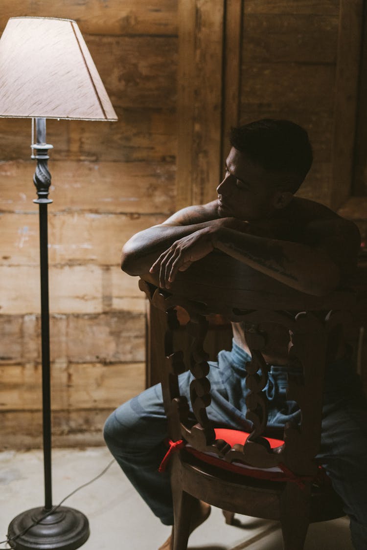 Photo Of A Man Sitting On A Chair In Pajamas